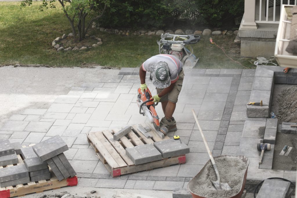Worker cutting pavers to interlock driveway