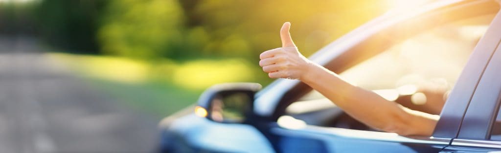 Woman inside her car thumb up for choosing the best asphalt paving option
