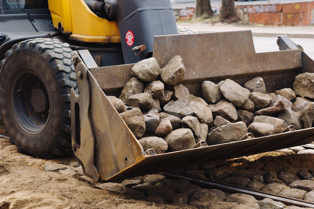 Excavation and Grading backhoe carrying rocks in bucket