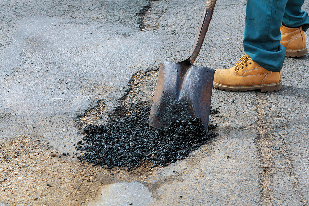 Road Asphalt Maintenance construction. New asphalt concrete, concrete kerb and orange safety