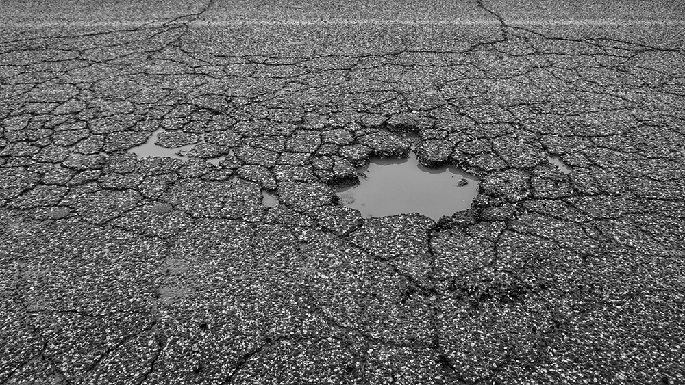 Pit on the asphalt caused by bad weather, traffic and poor Asphalt Maintenance 