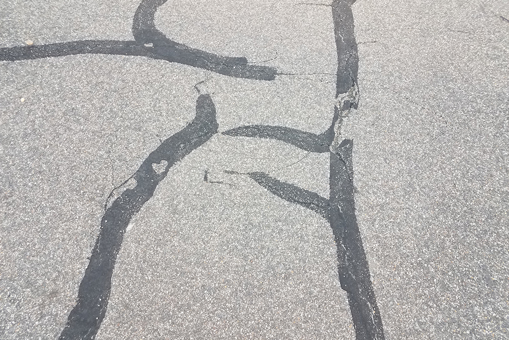 black asphalt surface with filled by crack sealing with coated by bitumen emulsion asphalt surface