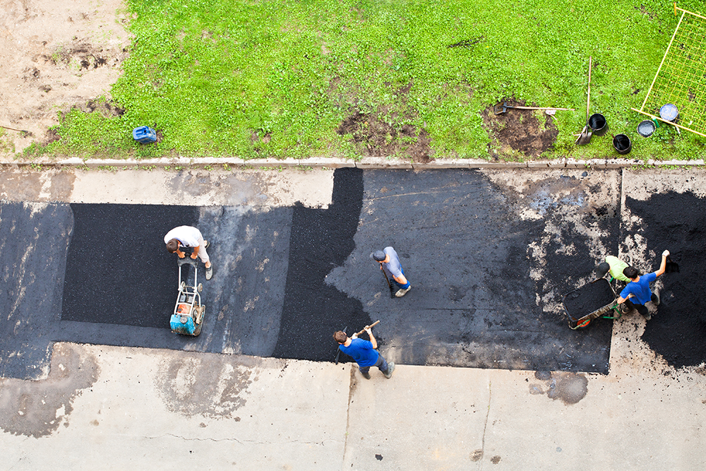 Unidentifiable men working on a new commercial paving of a concrete driveway at a business