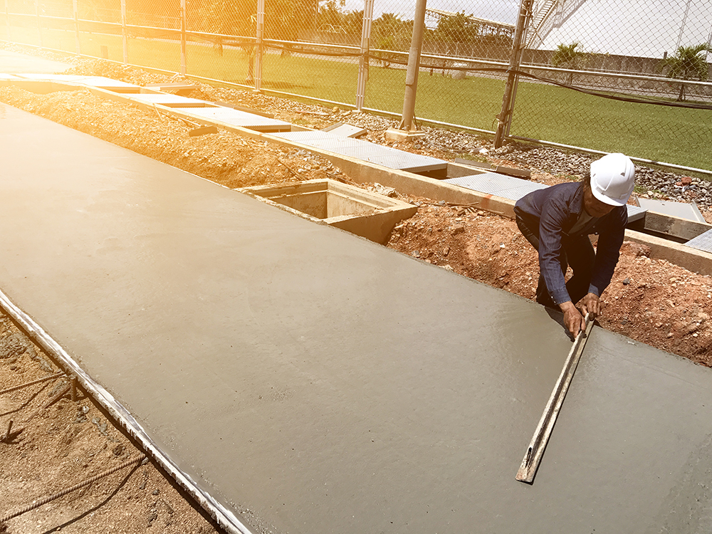Unidentifiable man levelling a new commercial paving walkway near a business