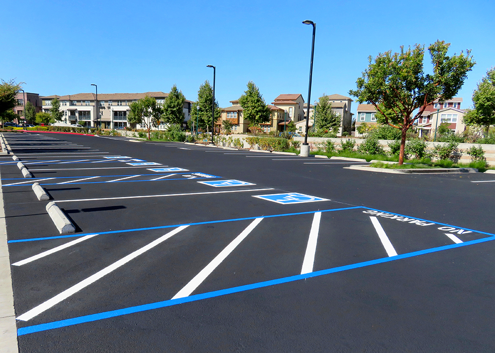 Freshly resurfaced asphalt paving and repainted handicap parking space in a parking lot