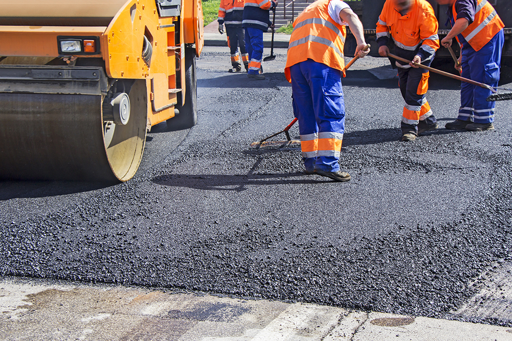 Roller and workers on asphalt paving and repair of commercial parking lot