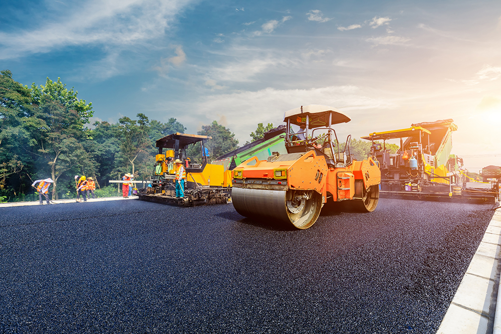 Commercial business site is laying new asphalt paving, road construction workers and road construction machinery scene
